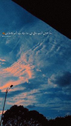 the sky is blue and pink with clouds in arabic writing on it as well as a street light