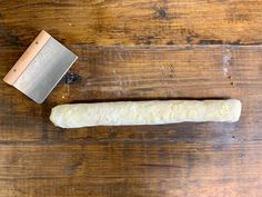 a piece of bread sitting on top of a wooden table next to a rolling pin