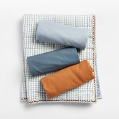 three different colored pillows sitting on top of a white and blue checkered pillow case