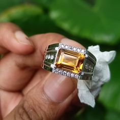 a person holding a ring with an orange and white stone in it's center