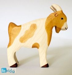 a wooden toy cow with horns on it's head and tail, standing in front of a white background