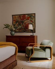 a bedroom with a bed, chair and painting on the wall