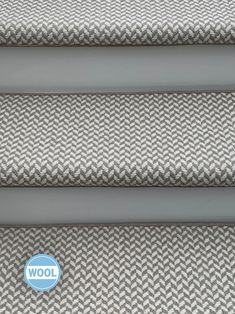 three grey and white chevroned fabric on the side of a stair treading