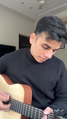 a young man is playing an acoustic guitar