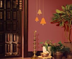 a room with red walls and gold bells hanging from the ceiling next to potted plants