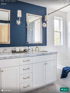 a bathroom with blue walls and two mirrors on the wall above the sinks, along with a bathtub