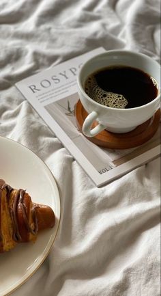 a pastry on a plate next to a cup of coffee and a book with the title roslap