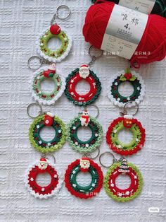 several christmas wreaths and rings are on a table next to some balls of yarn