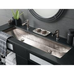 a bathroom sink sitting under a mirror next to a towel rack and potted plant