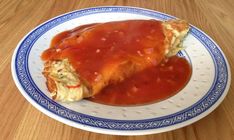 an enchilada on a blue and white plate covered in marinara sauce