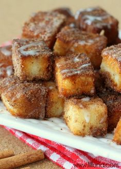 a pile of sugared doughnuts sitting on top of a white platter