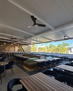 an empty restaurant with tables and chairs on the outside patio, overlooking palm trees in the distance