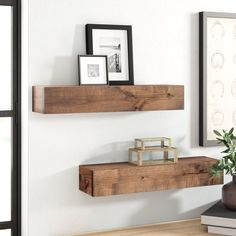 two wooden shelves on the wall near a vase and framed pictures with frames above them