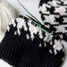 a black and white knitted hat next to a ball of yarn