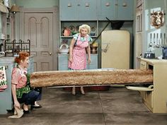 two women in a kitchen with a large log