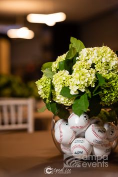 a vase filled with flowers and baseballs on top of a table