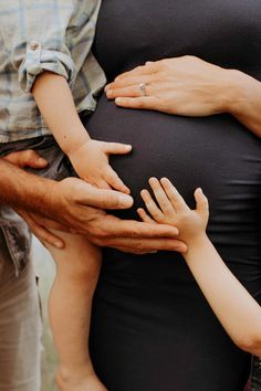 a pregnant woman with her hands on the belly of a man