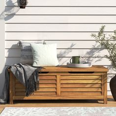 a wooden bench sitting on top of a patio next to a potted planter