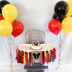 a mickey mouse themed birthday party with balloons and decorations on the table, including a cake