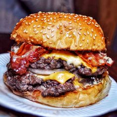 a cheeseburger with bacon and onions on a bun is served on a plate