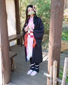 a woman dressed in traditional japanese clothing standing on a porch