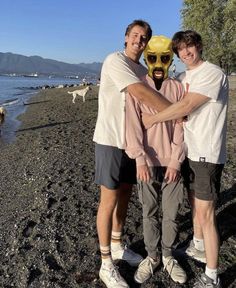 two men standing next to each other on a beach with a mask on their face