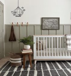 a baby's room with a white crib, rug and wall hangings