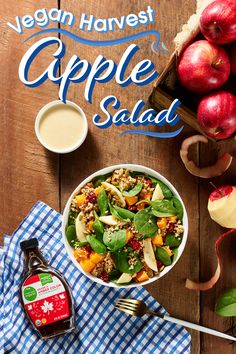 an apple salad with spinach, apples and dressing on a wooden table next to a bottle of maple syrup