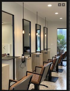 a row of chairs in a room with mirrors on the wall and lights hanging from the ceiling