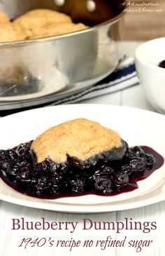 blueberry dumplings on a white plate next to a pan of muffins