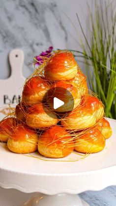 a white plate topped with croissants covered in icing next to a potted plant