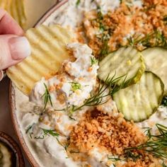 a bowl filled with cucumber, crackers and dill pickles on top