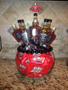 a red vase filled with liquor bottles on top of a counter