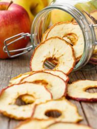 sliced apples are sitting on a table next to a glass jar filled with apple slices