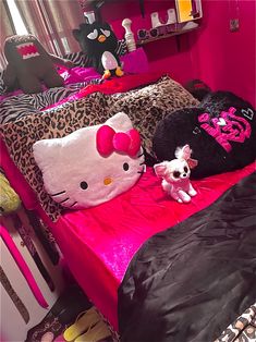 a hello kitty bed with pink sheets and black comforter, stuffed animals on it