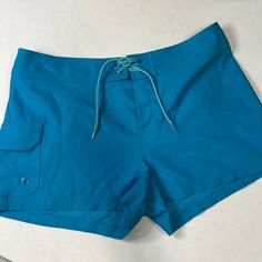 Lace Up Board Shorts In A Beautiful Aqua Blue Color. Single Pocket On Leg With Velcro Tab. Like New Condition Size S Waist Laying Flat: 16” Front Rise: 11” Inseam: 2.5” Blue Beachwear Bottoms In Short Length, Blue Shorts With Pockets For Poolside, Blue Beach Shorts With Pockets, Blue Shorts With Pockets For The Beach, Blue Shorts With Pockets For Vacation, Blue Short-length Beachwear Bottoms, Blue Short Length Beachwear Bottoms, Blue Shorts For Poolside, Short Length Bottoms With Pockets For Poolside