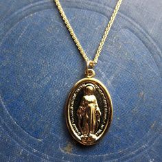 The Lady Madonna Necklace features a a high quality 14k gold wheat chain with a classic oval Mother Mary / Virgin Mary / Miraculous Mary Medal religious pendant. Perfect for layering!Chain: 14k Gold Fill Wheat Chain - 18" with a 2" extender.Pendant: Measures 15mm x 23mmMaterial:14k Gold Over BrassHandmade in NYC✦ GOLD FILL CARE ✦✧ Warm water and a soft cloth are the best thing you can do to maintain the beauty of your jewelry.✧ Jewelry polishing cloths work great and are non-abrasive.✧ Salt wate 14k Gold Necklace With Miraculous Medal, Spiritual Style Oval Necklace With Adjustable Chain, Spiritual Oval Necklace With Adjustable Chain, Spiritual Yellow Gold Oval Necklace, Spiritual Oval Yellow Gold Necklace, 14k Yellow Gold Miraculous Medal Necklace, Yellow Gold Miraculous Medal Oval Pendant Necklace, Yellow Gold Oval Pendant Necklace With Miraculous Medal, 14k Yellow Gold Necklace With Miraculous Medal