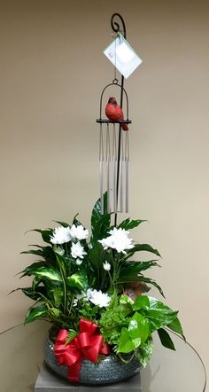 a glass table topped with a potted plant and an iron wind chime on top of it