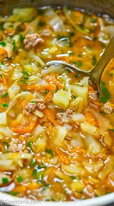 a ladle full of soup with meat and vegetables is being stirred by a spoon