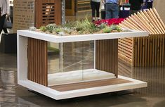 a white and wood table with plants in it at an indoor shopping mall or showroom