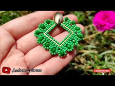 someone is holding a small green beaded square shaped broochle in their hand