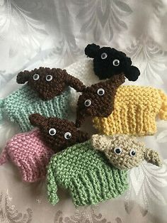 five crocheted stuffed animals with eyes on them sitting on a white cloth covered surface