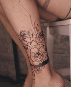 a woman's leg with flowers on it and a black ribbon around the ankle