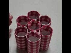 several red and white checkered paper cups stacked on top of each other with one hand reaching for the cup