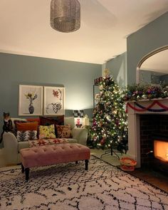 a living room filled with furniture and a christmas tree in front of a fire place