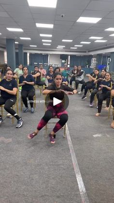 a group of people sitting in chairs with one person on the floor doing an exercise