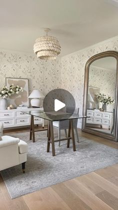 a living room filled with furniture and a mirror on top of a wooden floor next to a white chair