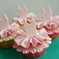 some cupcakes with pink frosting and bows on them are sitting on a table