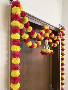 a doorway decorated with red, yellow and white pom - poms hanging from it's side