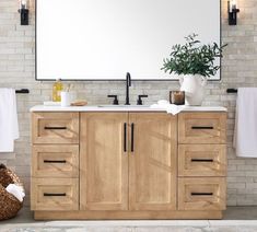 a bathroom vanity with two sinks and towels hanging on the wall next to brick walls